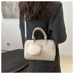 Detailed close-up of litchi texture on off-white boston bag with small round coin purse