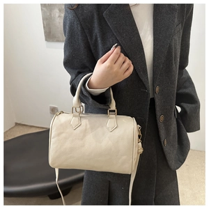 Detail of creamy white Boston bag with litchi texture on a model in a gray suit