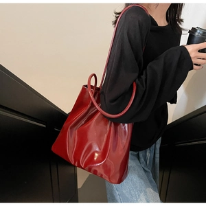Detail of burgundy glossy patent leather tote bag showing large capacity and shiny texture