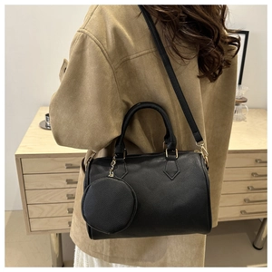 Black litchi grain Boston bag with small round pouch shown on a person shoulder