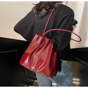 Detail of red oversized soft leather tote bag with glossy finish on shoulder