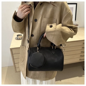 Detail of black pebbled leather Boston bag with round coin pouch on a wooden cabinet
