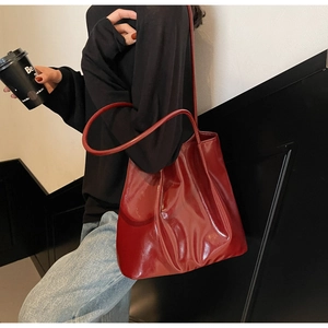 Lifestyle view of large burgundy patent leather tote bag on model over shoulder