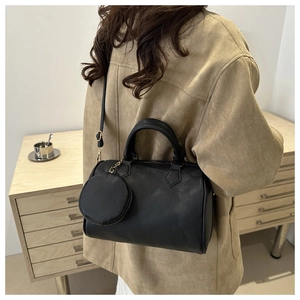 Black pebbled leather Boston handbag with a mini coin pouch charm on a model's arm