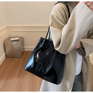Side view of a glossy black patent leather tote bag on model for daily commuting