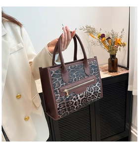 Leopard print tote bag with brown leather trim and metal zip pocket held by a model