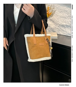 Detail of suede tote bag with white faux shearling trim and decorative bell charm