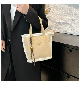 Macro shot of beige suede shoulder bag with fleece trim and fashion logo detail