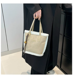 Detail of plush beige tote bag with lamb wool trim and FASHION label on suede fabric