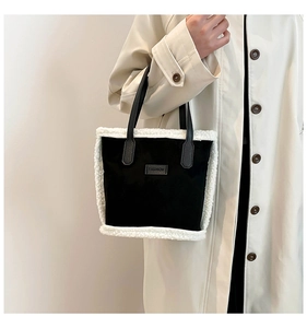 Détail du sac à main en daim noir avec bordure en peluche blanche et écusson en cuir