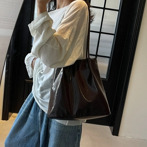 Deep brown glossy leather tote bag with long straps shown on a model for casual wear
