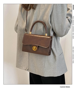 Detail of vintage brown textured leather crossbody bag with golden metal lock and round handle