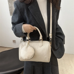Classic cream-colored Boston bag with pebbled leather texture and mini coin purse charm