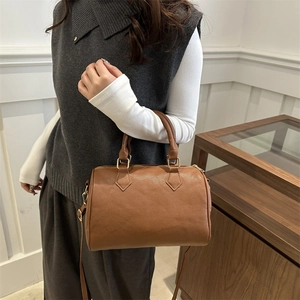 Brown lychee leather Boston bag with dual handles and gold-tone hardware on a model
