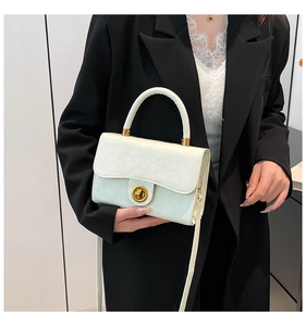 Chic cream white rectangular handbag with gold ring clasp held by model in black suit