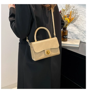 Detail showing beige leather crossbody bag worn by model with gold twist lock closure