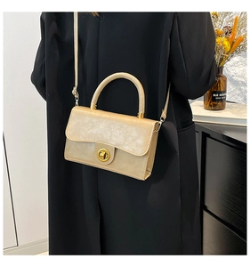 Detail of apricot crossbody bag with marble texture and golden twist lock on a model