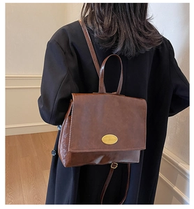 Detail of dark brown vintage backpack showing refined oil wax leather and gold hardware