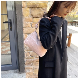 Detail of light pink wrinkled texture handbag with knotted strap on model shoulder