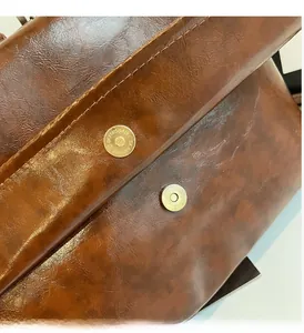 Macro shot of light gold magnetic clasp and oily wax leather texture on brown backpack