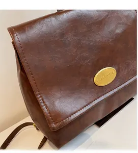 Detail of vintage oil wax leather backpack showing brown texture and gold metal plaque