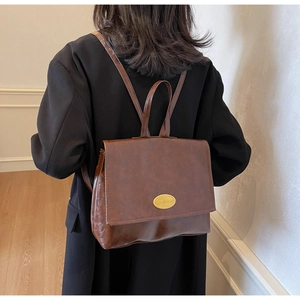 Detailed back view of a retro dark brown PU leather backpack on a female model