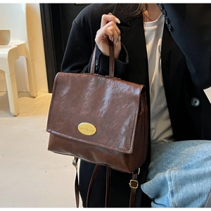 Detail of dark brown vintage faux leather backpack with gold clasp and slim shoulder strap