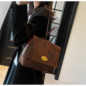 Detail view of dark coffee vintage leather backpack with gold metal plaque on model