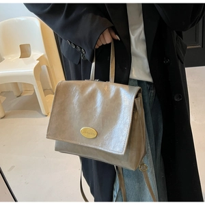 Detail view of khaki grey wrinkled leather handbag with gold metal logo plaque