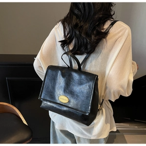 Detail of a vintage black faux leather backpack with gold buckle and smooth oily finish