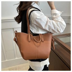 Detail of caramel brown faux leather tote with white contrast stitching and tie-knot side