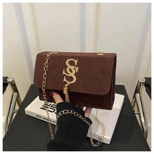 Detailed macro of dark brown matte leather bag with golden logo and metal tassel detail