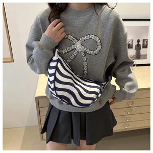 Detail of blue and white wavy stripe canvas half-moon crossbody bag on a model