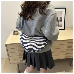 Detailed back view of a blue and white striped crescent crossbody bag on a model