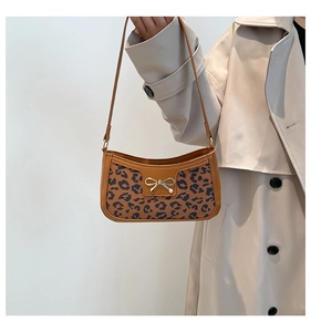 Close-up of leopard print shoulder bag with golden bow detail and brown leather trim