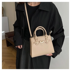 Detail of beige faux leather handbag with gold turn-lock closure and elegant top handle