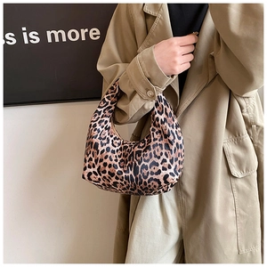 Sac hobo croissant à imprimé léopard porté par un mannequin en trench-coat kaki