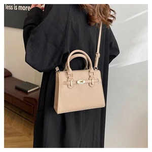 Vue détaillée du sac à main beige élégant porté sur un manteau en laine noire