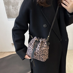 Leopard-Beuteltasche mit Kordelzug und schwarzem Gurt am Modelmantel präsentiert