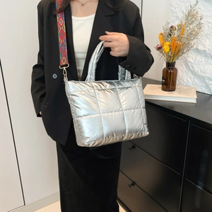 Sac cabas argenté matelassé avec bandoulière géométrique dans un décor minimaliste