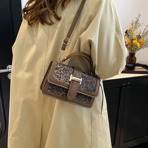 Vintage leopard print crossbody bag with brown leather trim worn by model in home setting
