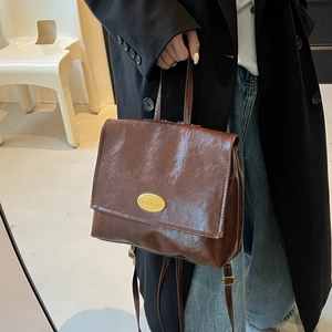 Retro coffee brown leather backpack with glossy textured finish and gold logo plate