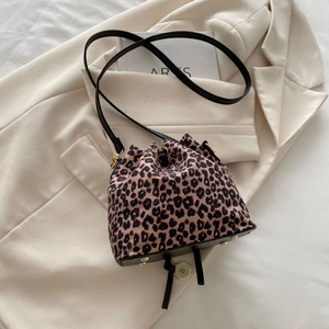 Detailaufnahme der Leoparden-Beuteltasche mit Goldnieten und Kordelzug auf einem beigen Blazer