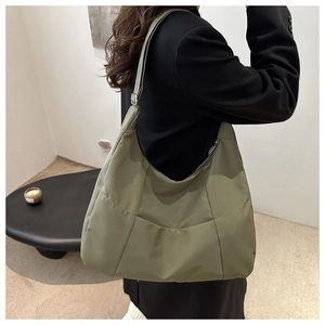 Detail view of large olive green canvas hobo bag with zip pocket on a model