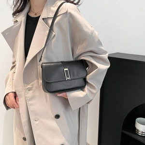 Minimalistische schwarze Leder-Umhängetasche mit Goldschließe zum beigen Trenchcoat