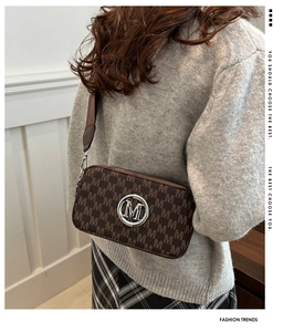 Detail of crossbody camera bag with brown M letter monogram and silver metal logo