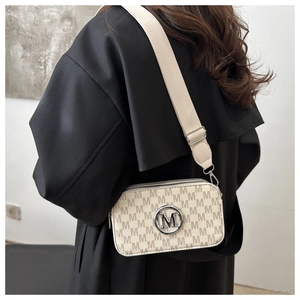 Detail of cross-body camera bag with beige M-monogram pattern and silver logo