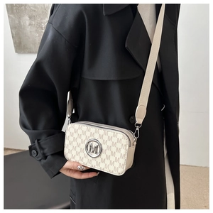 Detail of cream camera bag featuring all-over M monogram print and gold metallic logo