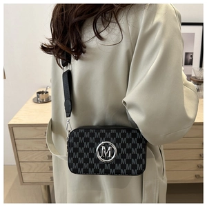 Detail of crossbody bag featuring M letter print and round silver metal logo on front