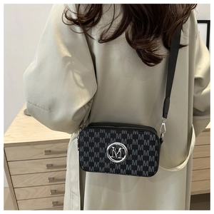 Detail of crossbody bag with grey letter M pattern and silver metallic logo hardware